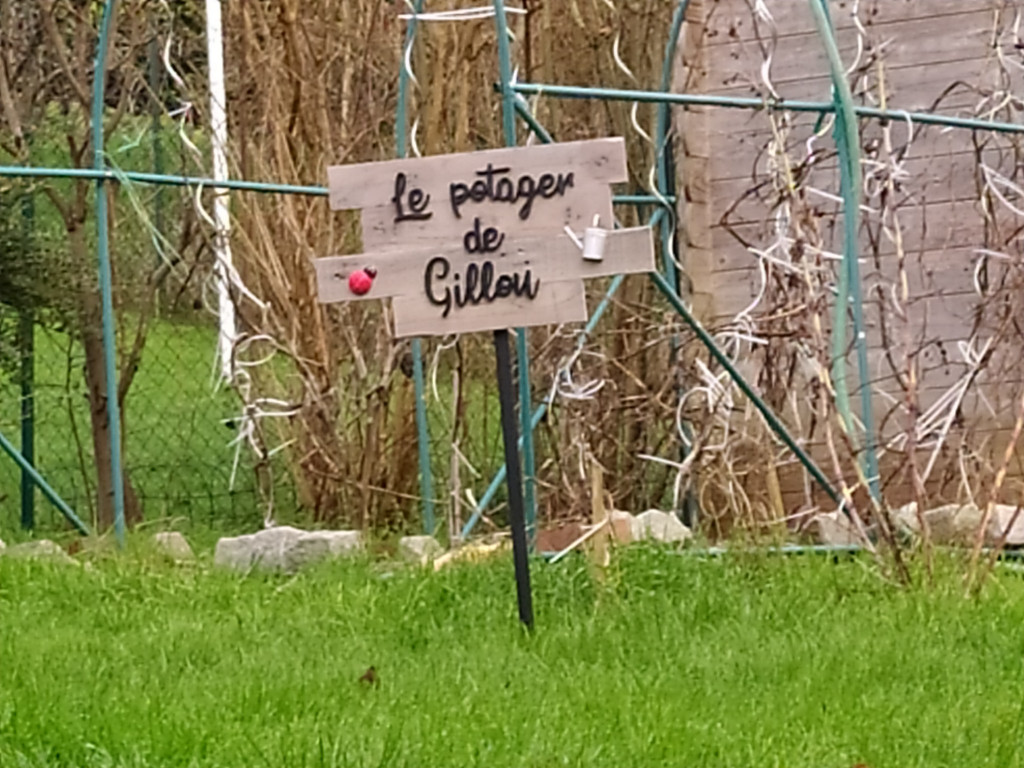 Pancarte "Le potager de Gillou" mis en situation dans le jardin.
